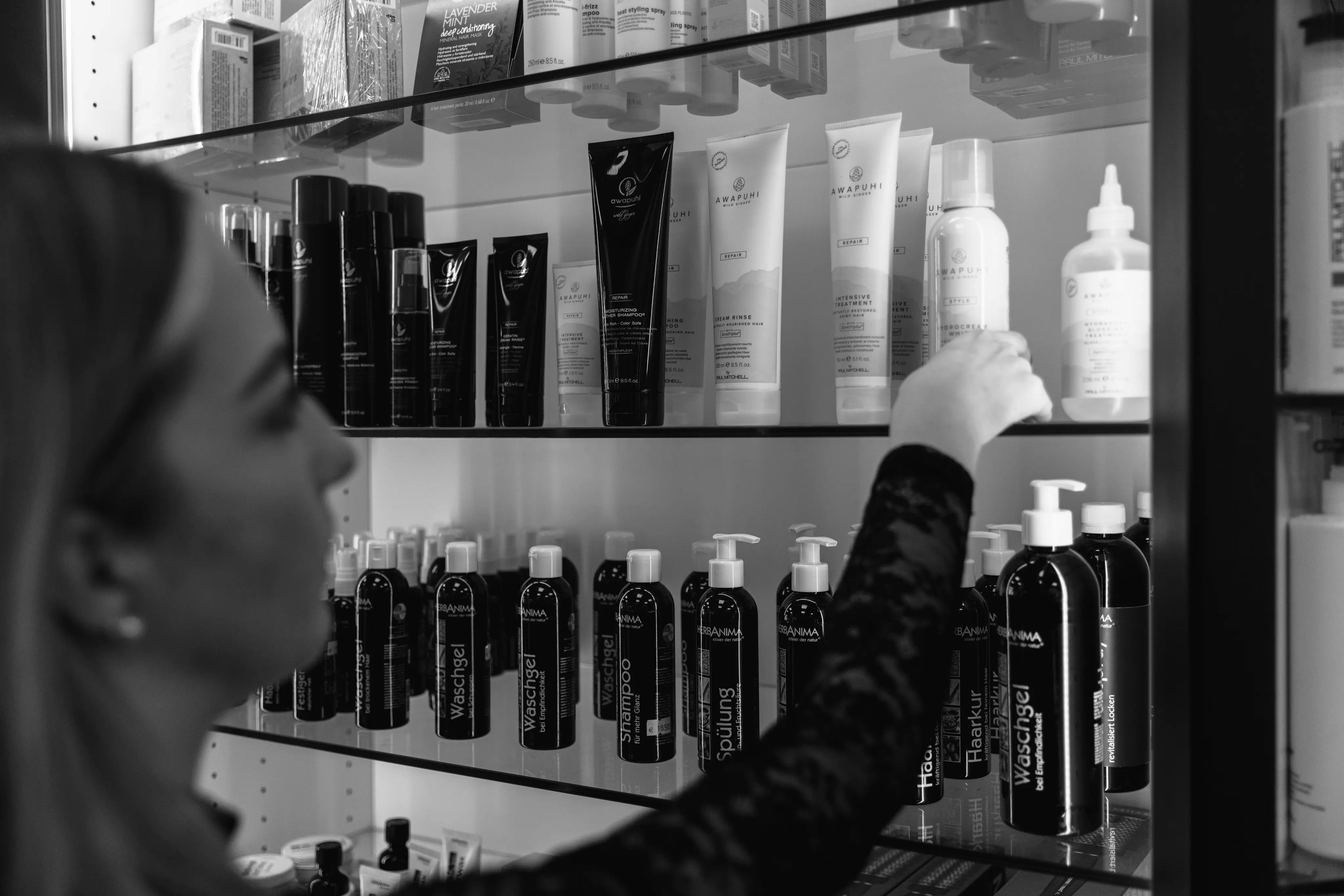 Mitarbeiterin des Coiffeur Hofstetter Salons, die Haarpflegeprodukte im Regal sortiert